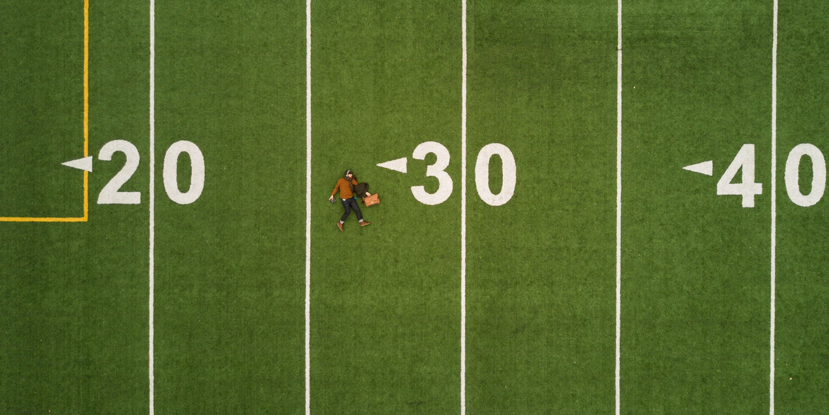 Person lying down on a football field near the 30 yard line