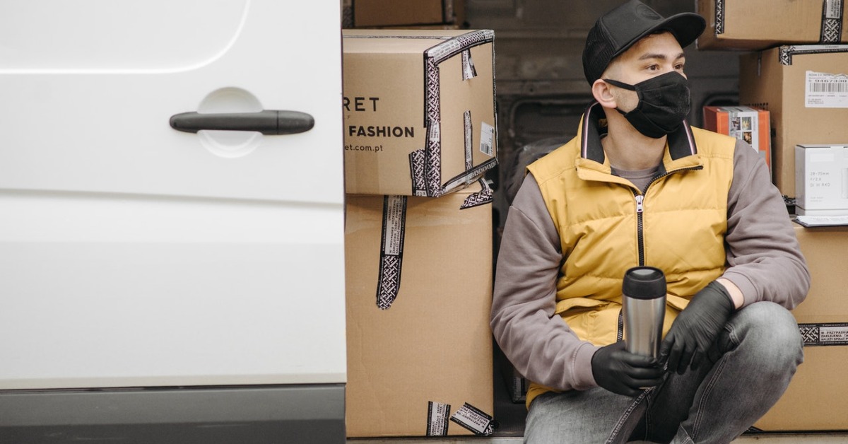 Man with a face mask sitting near brown boxes